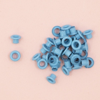 Ilhós azuis de plástico redondos sobre fundo cor-de-rosa