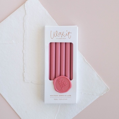 Caixa branca com seis velas cor-de-rosa e selo de cera rosa em papel branco