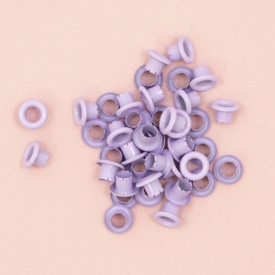 Conjunto de ilhós de plástico lilás sobre superfície creme