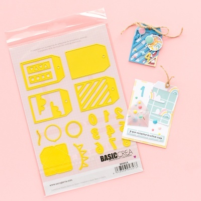 Moldes amarelos para tags e números em embalagem transparente e duas etiquetas decorativas coloridas suspensas.