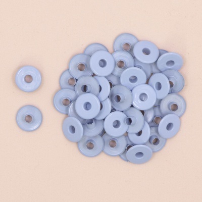 Discos plásticos cinza claro com furo central sobre fundo bege