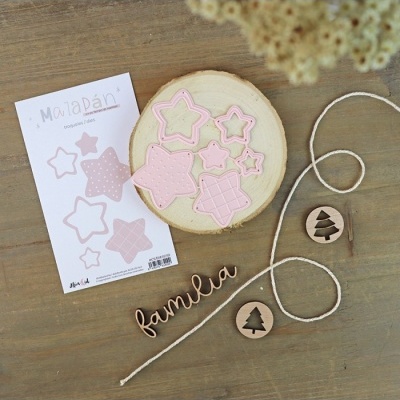 Conjunto de estrelas rosa em madeira clara com elementos decorativos de madeira e papelaria sobre mesa de madeira.