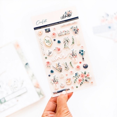 Folha de autocolantes florais decorativos em tons pastel segurada por mão