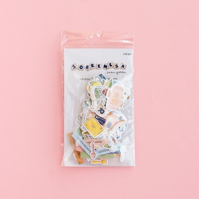 Pacote transparente com recortes de papel coloridos e etiquetas sobre fundo rosa