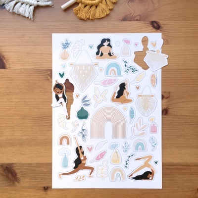 Folha com autocolantes de yoga, arcos e motivos boémios sobre mesa de madeira clara