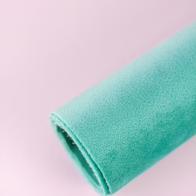 Rolo de tecido azul turquesa macio num fundo rosa claro