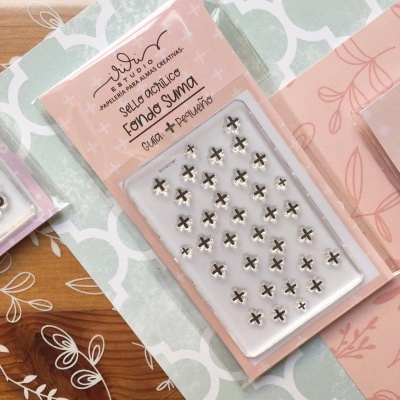 Selo acrílico com símbolos de cruz em embalagem rosa, sobre papéis decorativos