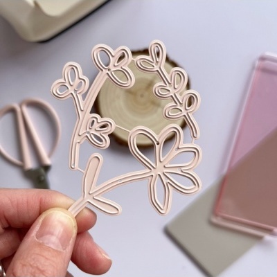 Recorte decorativo em forma de flor bege segurado por mão