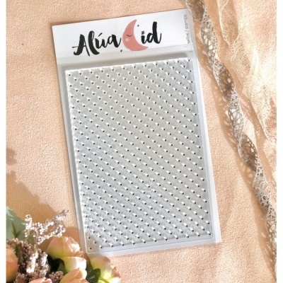 Pacote de strass adesivos prateados com etiqueta Alúa Cid sobre superfície rosa e flores
