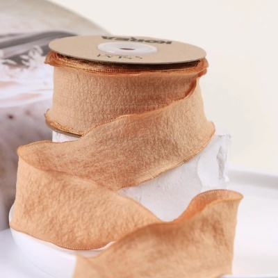 Fita decorativa cor pêssego com bordas douradas enrolada em carretel