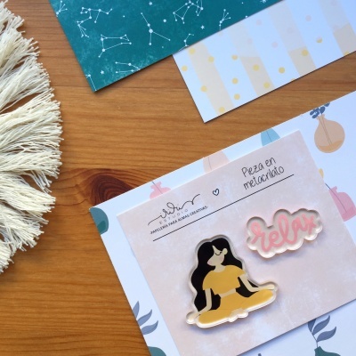 Dois pins decorativos sobre papel com texto em fundo de mesa de madeira