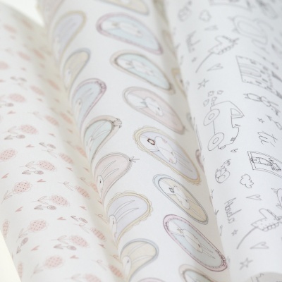 Três rolos de papel de embrulho com padrões infantis variados, coloridos e em preto e branco