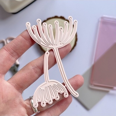 Corta-moldes de metal em forma de flores segurado por mão sobre fundo neutro