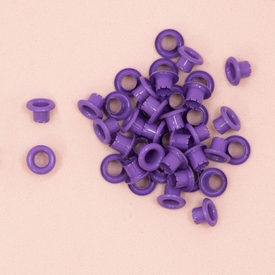 Peças plásticas roxas com círculos metálicos dispersas numa superfície rosa