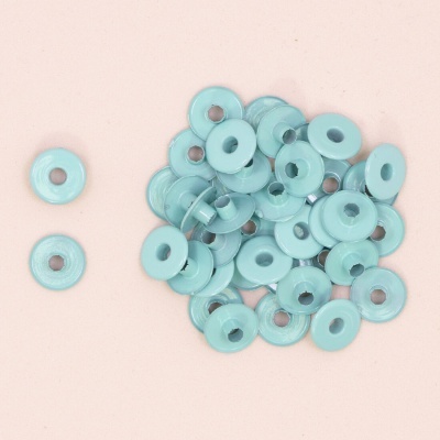 Botões redondos de plástico azul claro com furo central sobre fundo cor de salmão