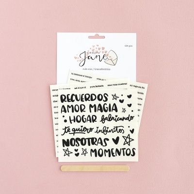 Folhas de transferências de letras em papel branco com texto em preto e embalagem da marca Jane sobre fundo rosa