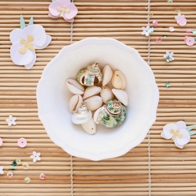 Tigela branca com conchas sobre esteira de bambu decorada com flores de papel
