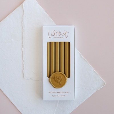 Conjunto de seis varetas de lacre caramelo em embalagem branca com selo dourado e fundo rosa e branco