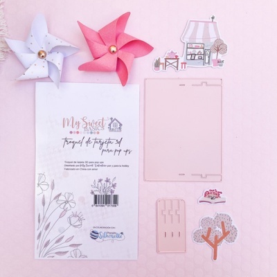 Conjunto de papel para montar casa decorativa com peças em rosa e branco sobre fundo rosa claro
