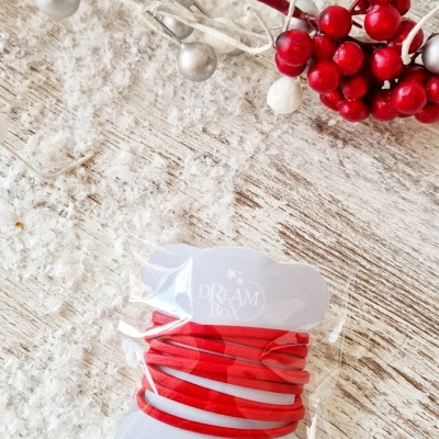 Elásticos vermelhos para cabelo embalados com decoração de bagas prateadas e vermelhas.