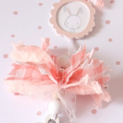 Colar decorativo com flor de madeira e fitas rosa claro com desenho de coelho.