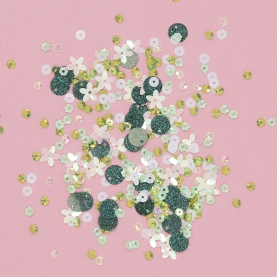 Lantejoulas coloridas e em forma de flor sobre fundo rosa