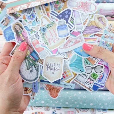 Mãos seguram autocolantes coloridos sobre tecidos dobrados em padrões florais e de corações