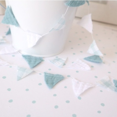 Bandeirinhas de tecido azul e branco em torno de balde branco com superfície de pontos azuis