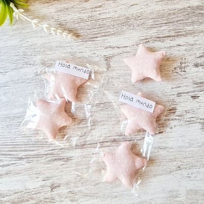 Estrelas cor de rosa em tecido com padrão de pontos brancos em fundo de madeira clara