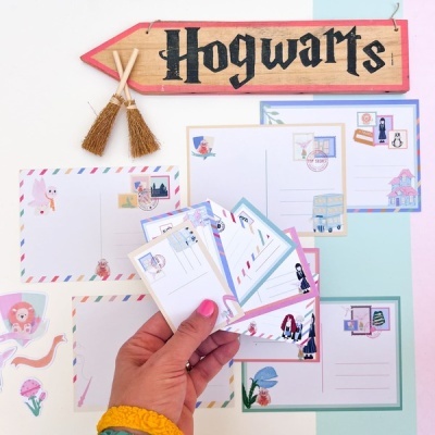 Cartões postais temáticos e placa de madeira com texto HOGWARTS e mini vassouras