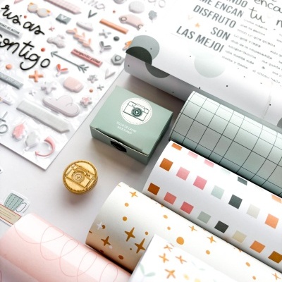 Rolos de papel decorativo, caixa verde e folhas adesivas com palavras e desenhos coloridos