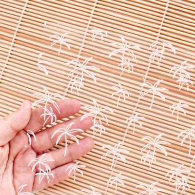 Manta transparente com padrão de palmeiras brancas sobre superfície de madeira