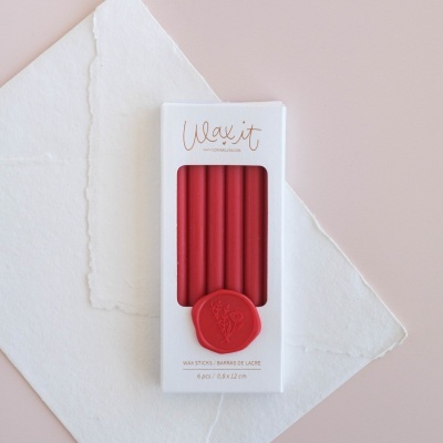 Pacote branco com varetas de lacre vermelhas e selo em cera sobre papéis brancos