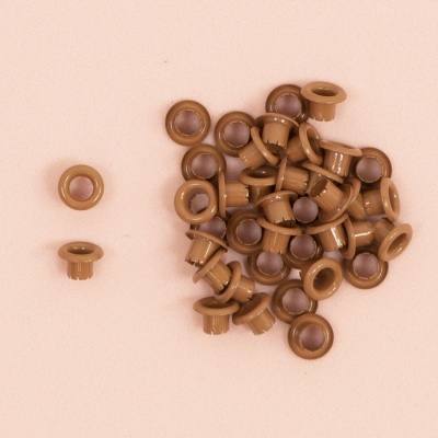 Peças plásticas castanho claro redondas com centro escuro sobre fundo cor de rosa