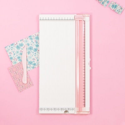 Máquina recortadora branca e rosa com papéis decorativos e ferramenta de corte