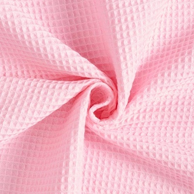 Tecido rosa com padrão waffle torcido para mostrar textura