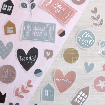 Folha de autocolantes com corações, casas, folhas e textos em tons pastel.