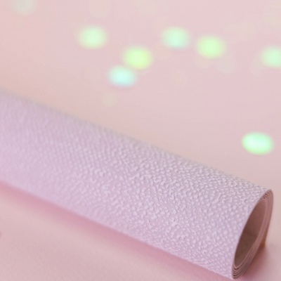 Rolo de papel texturado rosa claro com confetes brilhantes numa superfície rosa