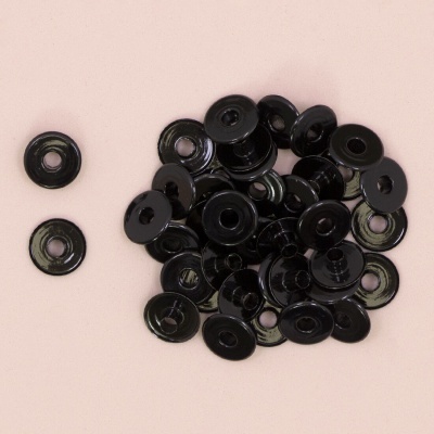 Molas de pressão negras em metal sobre fundo rosa