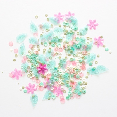 Lantejoulas coloridas em forma de flores e folhas sobre fundo branco