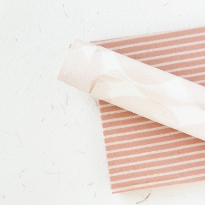 Tecidos com padrões geométricos e riscas sobre fundo branco texturizado