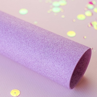 Bobina de papel roxo com lantejoulas iridescentes sobre fundo roxo