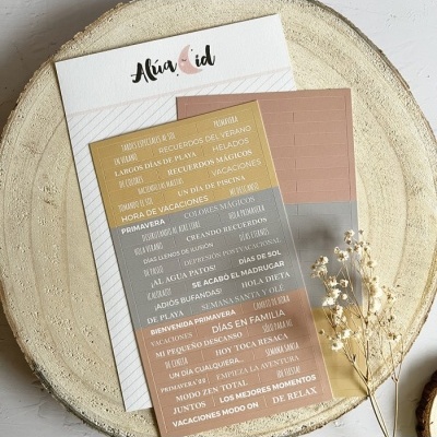 Cartão decorativo com padrões geométricos em tons de bege, rosa e dourado com envelope branco e ramo seco de flores