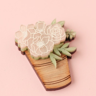 Broche em forma de vaso de flores com flores rosa claro e folhas verdes