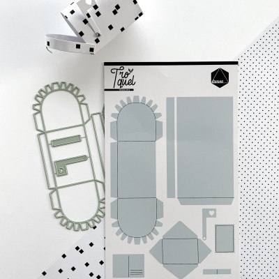 Plano de corte em papel cinzento e peça metálica para montagem de caixa