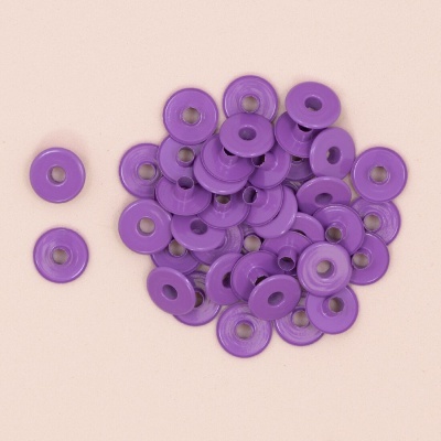 botões roxos redondos com centro metálico sobre superfície bege