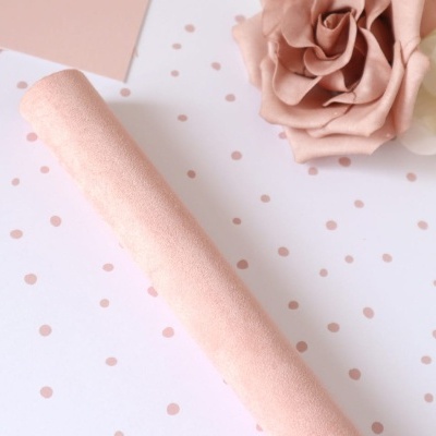 Rolo de tecido cor de rosa suave sobre papel branco com bolinhas cor-de-rosa e flor artificial cor-de-rosa