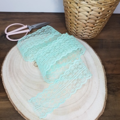 Fita de renda azul claro sobre madeira, com tesoura e vaso de planta