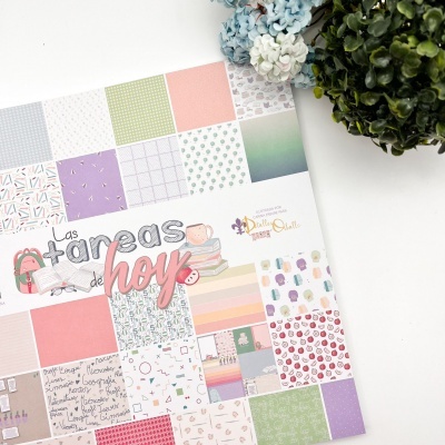 Bloco de papel decorativo com padrões variados em tons pastel junto a flores decorativas