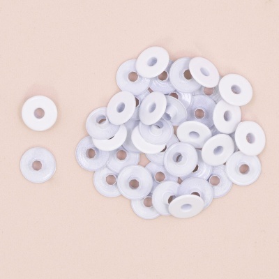 Molas de costura brancas circulares com furo central sobre superfície bege